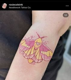 a yellow and pink moth tattoo on the left upper half of the arm, with stars around it