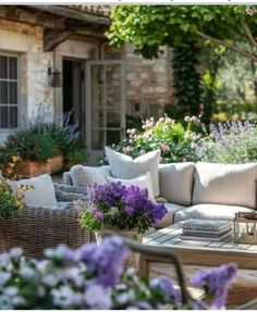 an outdoor living area with couches, tables and flowers