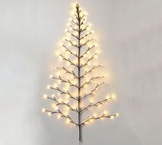 a lighted christmas tree is shown against a white wall with lights on the top and bottom