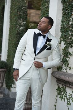 a man in a tuxedo leaning against a wall