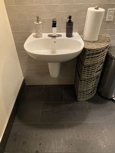 a white sink sitting under a bathroom mirror next to a trash can