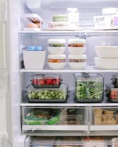 an open refrigerator filled with lots of food and containers full of salad, fruit, and vegetables