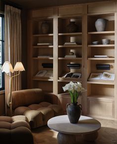 a living room filled with lots of furniture and bookshelves next to a window