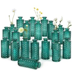 a large group of green vases with flowers in them sitting next to each other