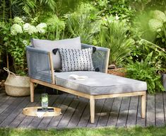 a chaise lounge chair sitting on top of a wooden deck in front of plants