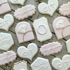 decorated cookies are arranged on a wooden table with white frosting and pink icing