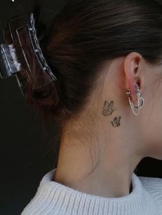 a woman with a small butterfly tattoo on her left side behind her ear, looking down at the ground