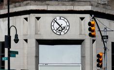 a large clock on the side of a building with traffic lights in front of it