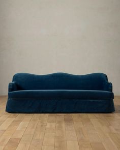 a blue couch sitting on top of a hard wood floor next to a white wall