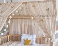 a canopy bed with white curtains and pom poms