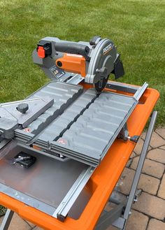 an orange table saw sitting on top of a metal tray with tools attached to it