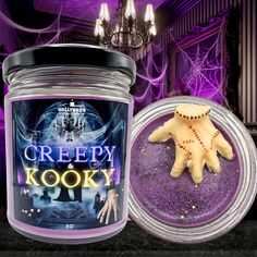 a candle that is next to some kind of halloween decoration in a jar with the words creepy kooky on it