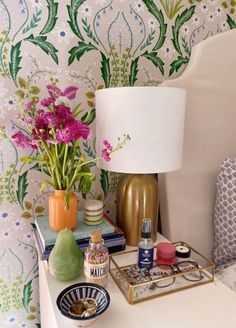 a table topped with vases filled with flowers next to a lamp