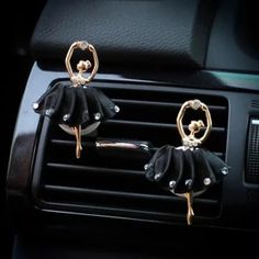 two pairs of black and gold ballerinas are attached to the dashboard of a car