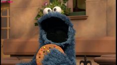 the cookie monster is holding a doughnut in his hand