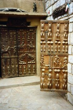 two wooden doors with carvings on them in front of a brick wall and stone floor