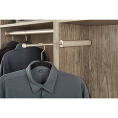 three shirts hanging on a rail in front of a wooden closet with two open doors