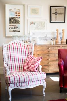 two red chairs sitting next to each other in front of a dresser and chest of drawers