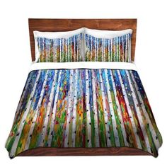 a bed covered in a colorful comforter next to a wooden headboard and night stand