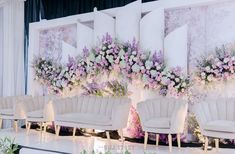 chairs are lined up in front of a wall with flowers and greenery on it