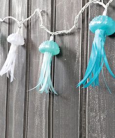 jellyfish string lights are hung on a wooden fence with white and blue streamers