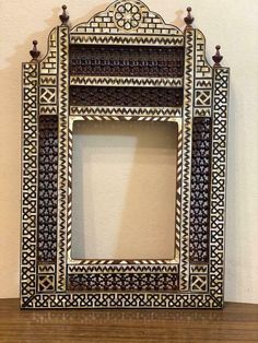 an ornate white and black frame on top of a wooden table