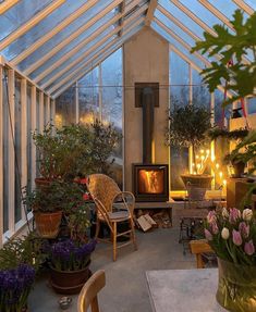 a room filled with lots of potted plants next to a fire burning in a fireplace