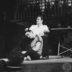 black and white photograph of two people sitting on the ground with one person touching his head