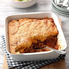 a casserole dish with meat and vegetables in it on a wooden cutting board