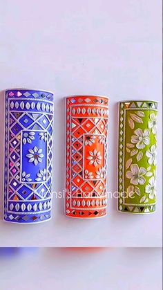 four different colored vases are lined up in a row on a white surface,