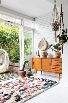 a living room with white walls and lots of plants in the window sill area