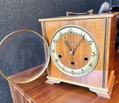 an old fashioned clock sitting on top of a wooden table