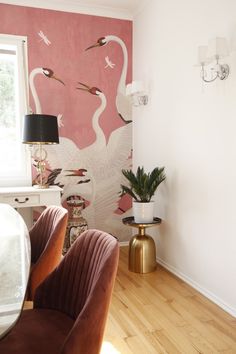 two chairs in front of a wall with swans on it and a lamp next to them