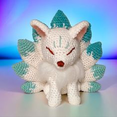 a white and blue knitted toy with horns on it's head, sitting in front of a blue background