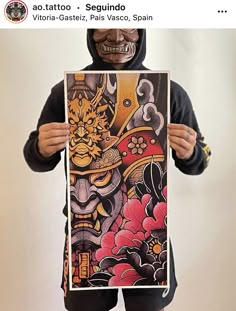 a person in a black hoodie holding up a poster with an image of a demon on it