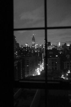 the city lights are lit up at night from an apartment window in black and white