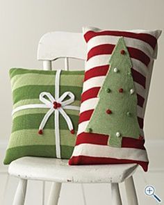 two christmas pillows sitting on top of a white chair next to a green and red pillow