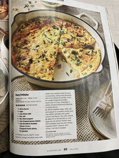 an open magazine with a pizza in it on a table next to utensils