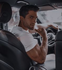 a man sitting in the driver's seat of a car with his hand on his chin