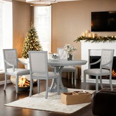 a dining room table with chairs and a christmas tree in the corner next to it