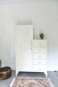 a white cabinet sitting next to a rug on top of a floor