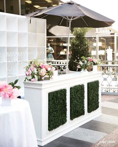 an outdoor bar with potted plants on it and a umbrella over the bar for shade