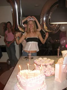 a woman standing in front of a table filled with cupcakes and cake covered cakes