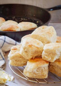 biscuits cooling on a wire rack in front of a skillet with buttery bread