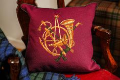 a red pillow sitting on top of a wooden chair next to a plaid throw pillow