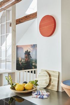 a bowl of fruit sitting on top of a counter next to a plate with lemons