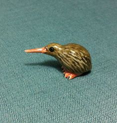 a small toy bird sitting on top of a blue carpeted floor next to a white wall