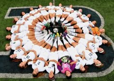 a group of people standing in a circle on top of a grass covered soccer field