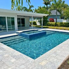 an empty swimming pool in front of a house with palm trees and landscaping around it