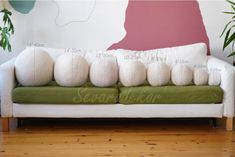 a green and white couch sitting on top of a hard wood floor next to a potted plant